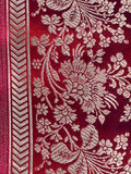 Close-up of a red fabric with intricate beige floral patterns